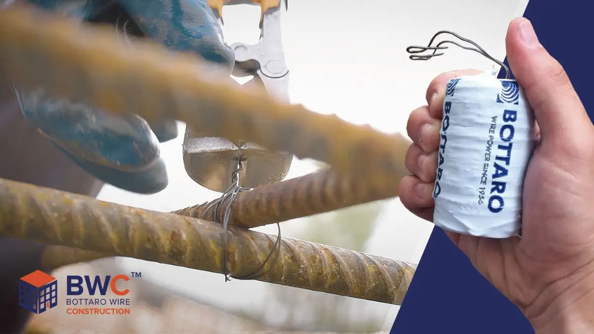 Mano che tiene bobinetta di filo di ferro per edilizia, sullo sfondo un cantiere edile